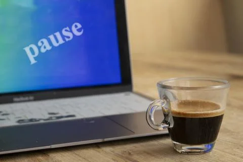 Espresso cup by laptop with pause text on screen for work break Stock Photos