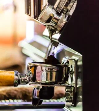 Espresso machine grinding roasted coffee bean into tamper. . Stock Photos