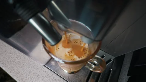Espresso Machine Pouring Fresh Coffee Into Clear Glass Mug with Milk Video stock 339180437