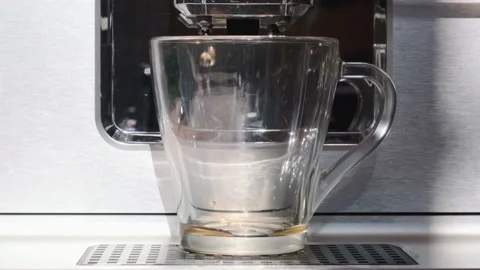 Espresso is poured into the glass Cup automatic coffee machine Stock Footage 135193683