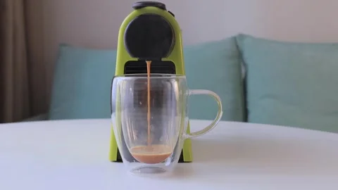 Espresso pouring from coffee machine into clear glass cup on white table Stock Footage 316370080
