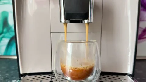 Espresso is Pouring from a Coffee Machine into a Glass, creating a delightful Stock Footage 304840548
