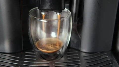 Espresso Pouring from Coffee Machine into Transparent Double Wall Glass Cup Stock Footage 257699831
