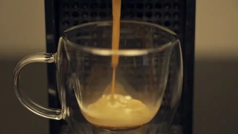 Espresso starting being poured into transparent cup in coffee machine. Slow Stock Footage 218245015