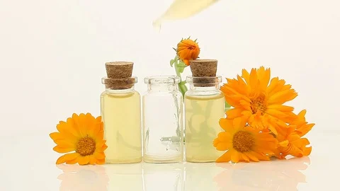 Essence of calendula flowers on white background in beautiful glass bottle Stock Footage 129346026