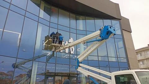 The essential maintenance of a glass facade using a boom lift is crucial for its Stock Photos
