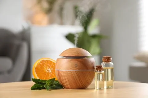 Essential oil diffuser, cosmetic products, mint and orange on wooden table .. Stock Photos