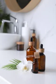 Essential oils and orchid flower on white table in bathroom Stock Photos