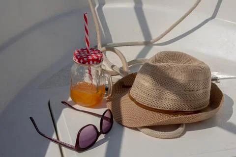 Essential supplies for a boating trip, a hat, sunglasses and  a cold drink Stock Photos