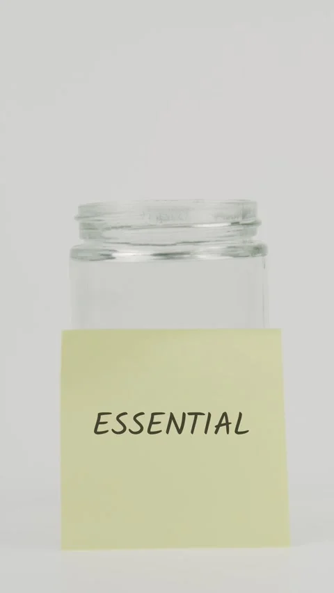 Essential text or word on yellow sticky note attached to glass jar with hand Stock Footage 311727186