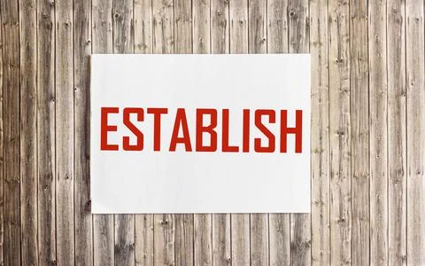 ESTABLISH word concept on notepad and on wooden table Stock Photos