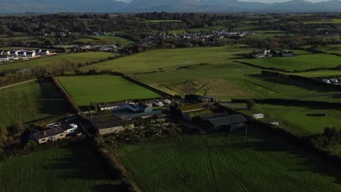 Establishing aerial view over patchwork Anglesey farm to reveal Snowdonia Stock Footage 254711365