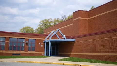 Establishing shot of red brick elementary school on gloomy day Stock Footage 89736934