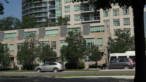 Establishing shot. Transit bus arriving at stop in front of building complex. Stock Footage 78306997