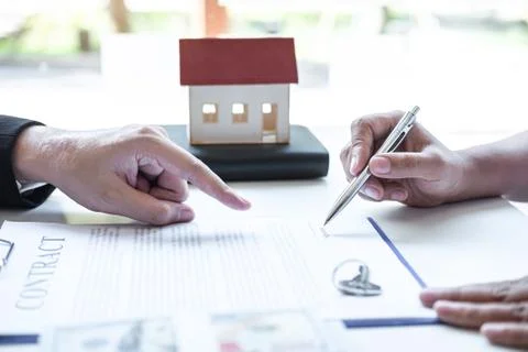 Estate agent broker pointing contract form to client signing agreement contra Stock Photos