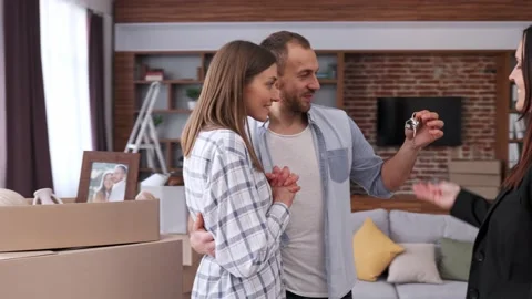 Estate agent giving bunch of keys from new house to young couple. Happy 스톡 동영상 176861486