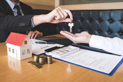 Estate agent giving house keys to client after signing agreement contract rea Foto stock