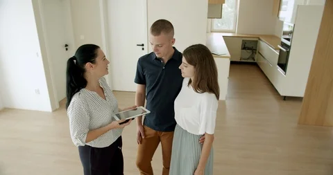 Estate agent using digital tablet with young couple in new house. Stock Footage 120524344