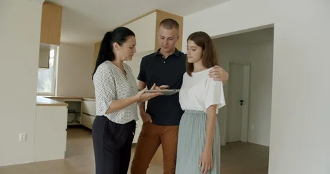 Estate agent using digital tablet in new apartment and showing young couple. Stock Footage 120524982