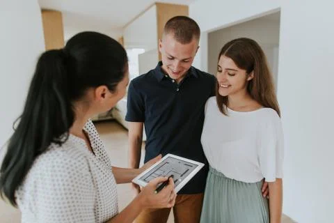 Estate agent using digital tablet showing young couple new house. Stock Photos