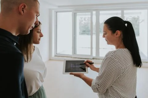 Estate agent using digital tablet showing young couple new house. Stock Photos