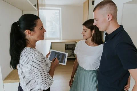 Estate agent using digital tablet showing young couple new house. Stock Photos