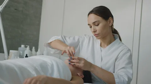 Esthetician massaging face, applying moisturizing cream Видео 126340733