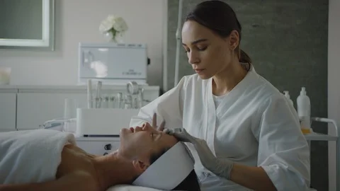 Esthetician massaging face, applying moisturizing cream Видео 126342385