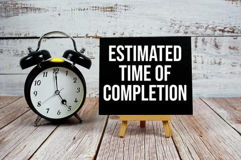 Estimated Time Of Completion text with easel and alarm clock on wooden back.. Stock Photos