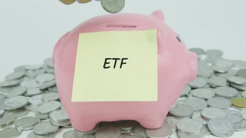 ETF Word Or Text on Yellow Note Paper and Hand Inserting Coins to Pink Piggy Stock Footage 301504261