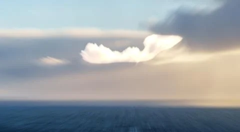 Ethereal cloud effect over silhouette land and sea in foreground. Stock Photos