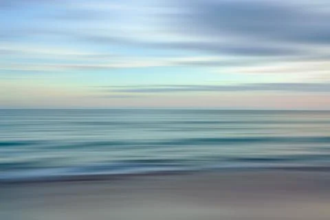 Ethereal waves flow in a blurred dance of blues and oranges in a serene sea.. Stock Photos