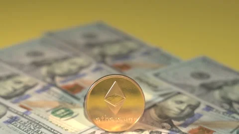 Ethereum ether cryptocurrency coins and many USD of 100 dollar bills on yellow Stock Footage 143645486