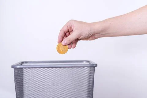 Etherium gold coin close-up on a gray background is thrown in the trash. Stock Photos