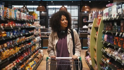 Ethnic black girl in casual clothes. She walking with shopping cart along Stock Footage 131087750