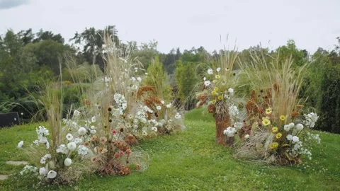 Ethnic boho wedding arch with composition of dried and pastel flowers on green Stock Footage 258750797