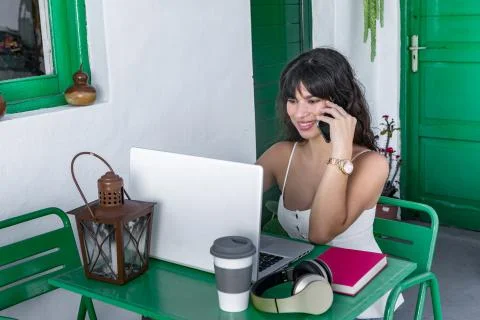 Ethnic freelancer using laptop and talking on smartphone Stock-Fotos