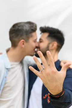 Ethnic guy demonstrating ring and embracing boyfriend after proposal Stock Photos