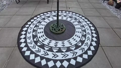 Ethnic patterned circular garden rug on grey paving stones modern living Stock Footage 342341363