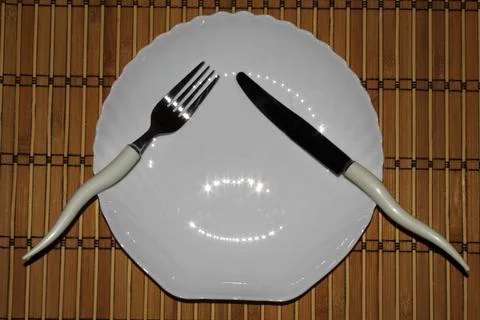 Etiquette fork and knife on a white plate on a mat background 写真素材