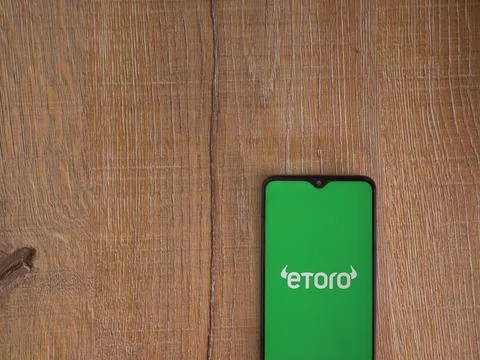 EToro app launch screen on smartphone on wooden background Stock Photos