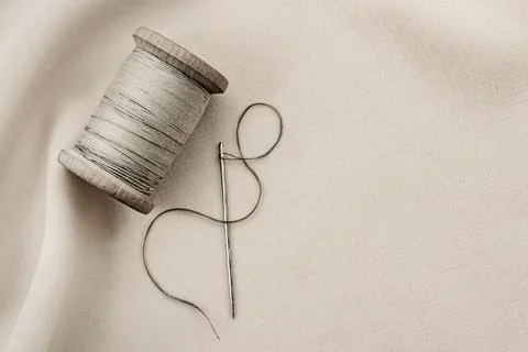 Etro needle and thread lie on the fabric. Tools for a tailor or seamstress. B Stock Photos