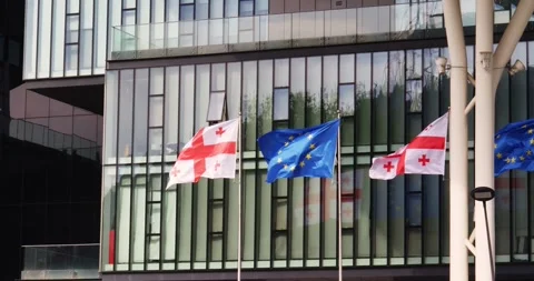 The EU and Georgian flags flutter against the background of the glass facade of Video stock 276206947