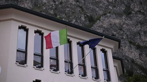 EU and Italian flags waving on a building under a blue sky Stock Footage 305555811