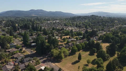 Eugene Oregon aerial view of homes with trees and distant mountains Видео 344995740