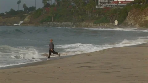 Euphoric male chasing waves on beach in Laguna Beach, California USA Stock Footage 101488560