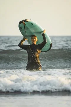 Euphoric young man with his surfboard on top of his head Stock Photos