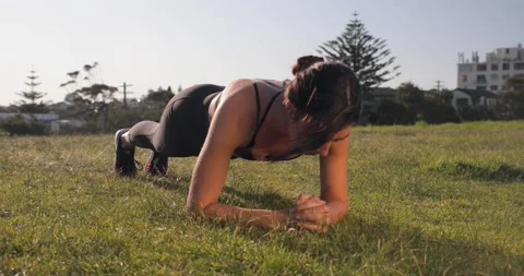 Eurasian female does exercise plank in the park during sunset Stock Footage 138252527