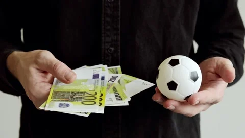 Euro banknotes and small soccer ball in hand. Corruption in football. Stock Footage 321069685
