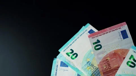 Euro banknotes drop and settle on a dark surface with copy space, showing cash Vidéo 328951381